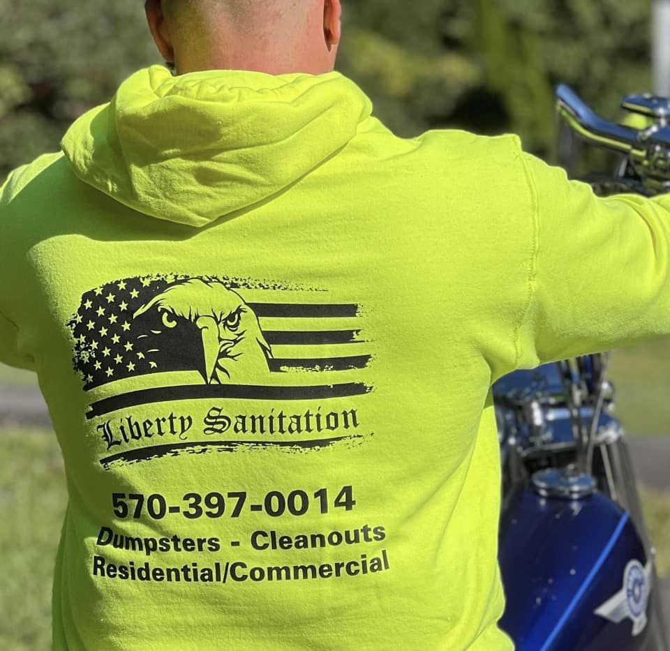Back of a hi-vis Liberty Sanitation hoodie reading Dumpsters, Cleanouts, Residential and Commercial